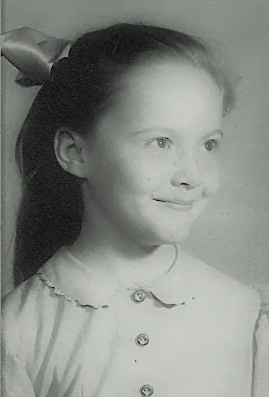 A young girl in a white dress is smiling.